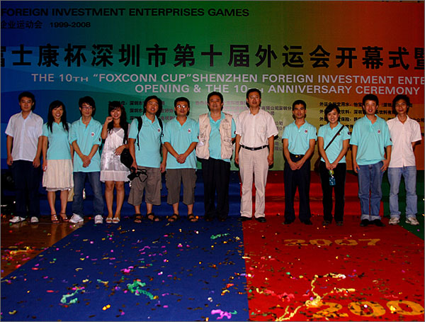 深圳市黑眼睛廣告有限公司參與外運會會務工作的部分員工和文總、徐總在開幕式背景版前留影